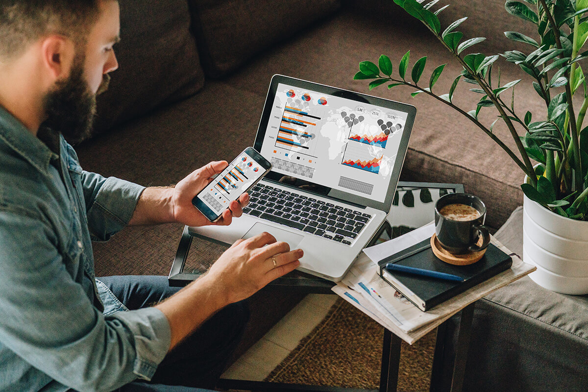 Man looking at statistics on laptop and mobile