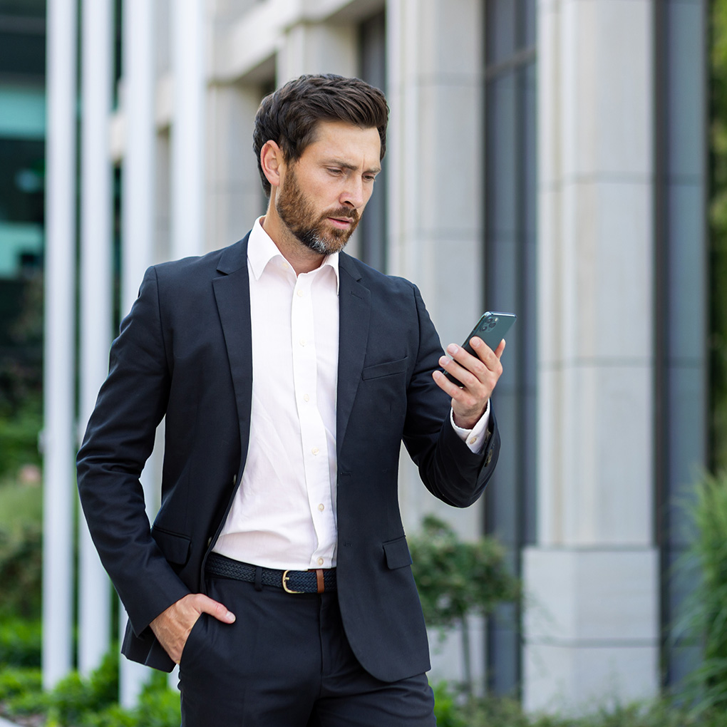 Business man looking in to his phone walking outside